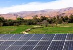 “Solar panels with farmland and mountains in the background, representing renewable energy and sustainable agriculture
