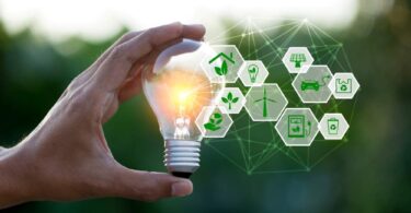 Hand holding a glowing light bulb with green energy and sustainability icons symbolising renewable technology innovation.
