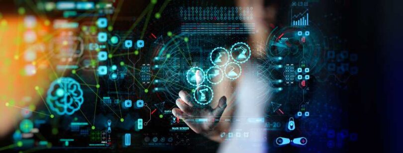 A person interacting with a digital interface displaying data visualisation, analytics icons and interconnected machinery graphics representing industrial monitoring technology.