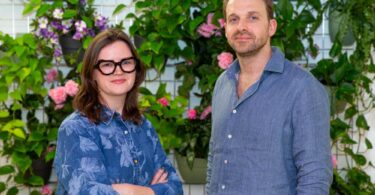 Kuppa co-founders standing in front of an indoor plant wall after the company’s acquisition by Octopus Energy.