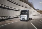Volvo heavy-duty truck driving on highway demonstrating new stop/start fuel-saving technology.