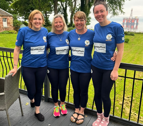 Four members of the Scotland the Wave rowing team standing together in matching blue shirts ahead of their Atlantic rowing challenge.