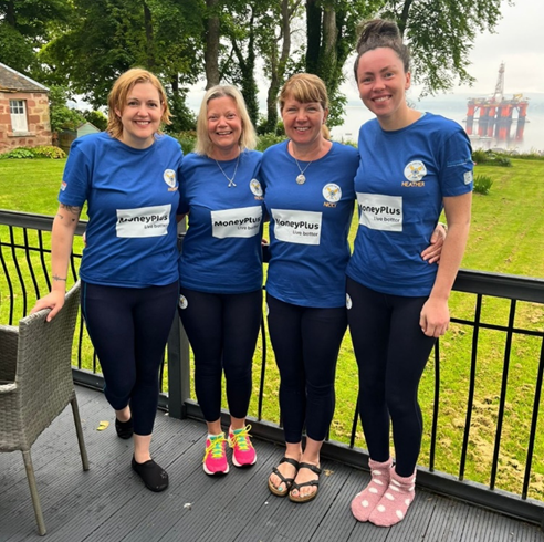 Four members of the Scotland the Wave rowing team standing together in matching blue shirts ahead of their Atlantic rowing challenge.