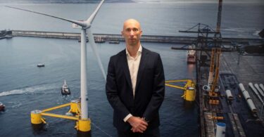 João Amaral, new CEO of Principle Power, photographed in front of a floating offshore wind turbine backdrop.