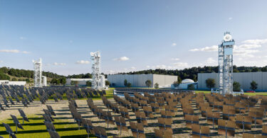 A solar-thermal facility with rows of solar collectors facing tall thermal energy towers at a 247Solar installation.