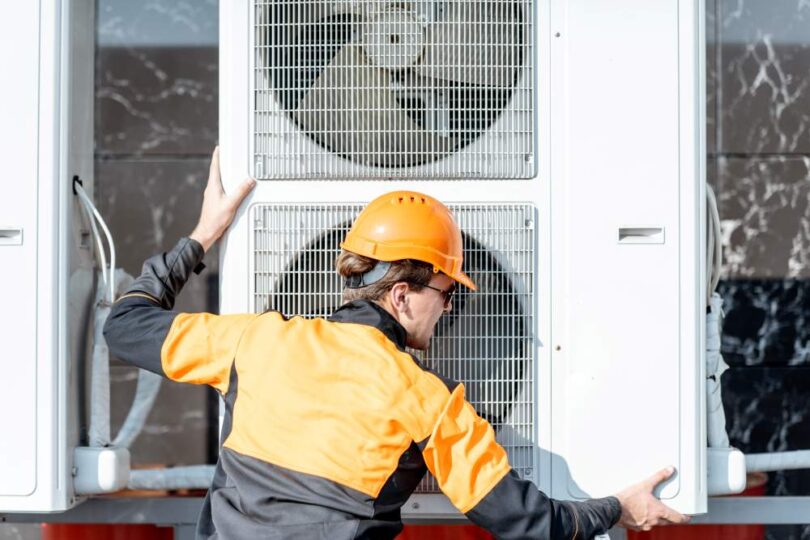 Engineer installing an air source heat pump on a residential building