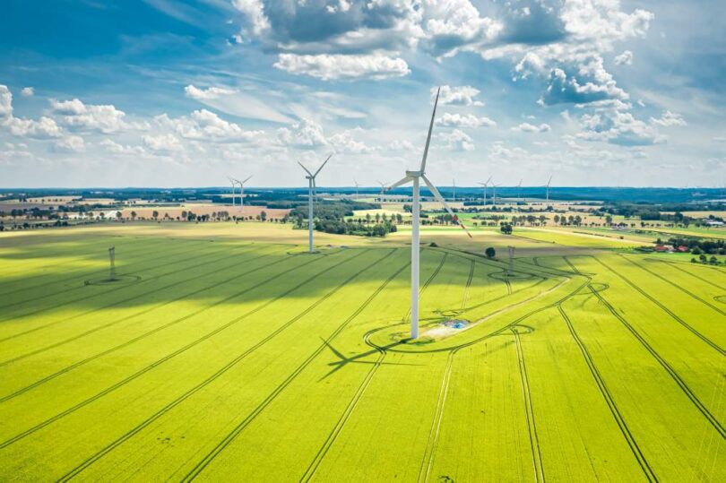 Renewable energy investment strategy illustrated by onshore wind turbines operating across agricultural landscape in Europe