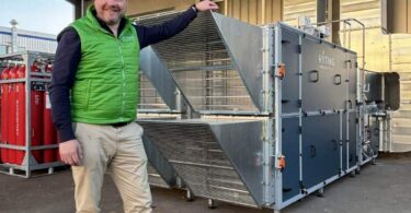 HYTING hydrogen hybrid heating system installation with CEO standing beside industrial air-heating unit