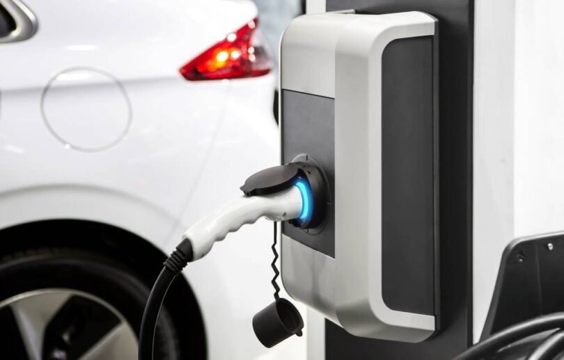 Electric vehicle market share in the UK with EV charging point connected to electric car