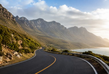 Coastal roadway infrastructure winding through mountainous terrain beside the ocean