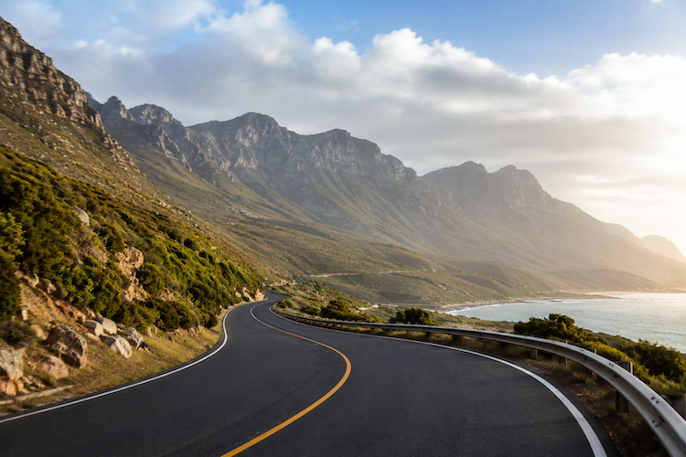 Coastal roadway infrastructure winding through mountainous terrain beside the ocean