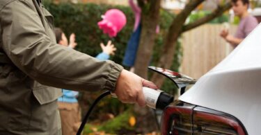 Driver charging an electric vehicle at home, representing the continued growth of electric vehicle adoption in the UK.
