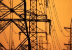 High-voltage electricity transmission towers supporting Europe's power grid infrastructure at sunset.
