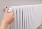 Close-up of a woman's hand adjusting a radiator thermostat valve