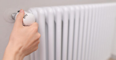 Close-up of a woman's hand adjusting a radiator thermostat valve