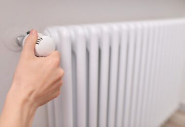 Close-up of a woman's hand adjusting a radiator thermostat valve