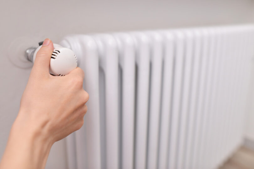 Close-up of a woman's hand adjusting a radiator thermostat valve