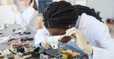 Portrait of a female engineer inspecting computer parts in a quality control lab.
