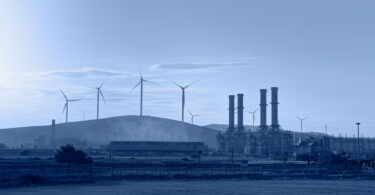 Silhouette of a natural gas processing plant alongside wind turbines generating electricity.