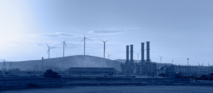 Silhouette of a natural gas processing plant alongside wind turbines generating electricity.