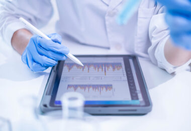 A woman in a laboratory setting writing notes on a document, appearing to be a scientist or doctor at work.