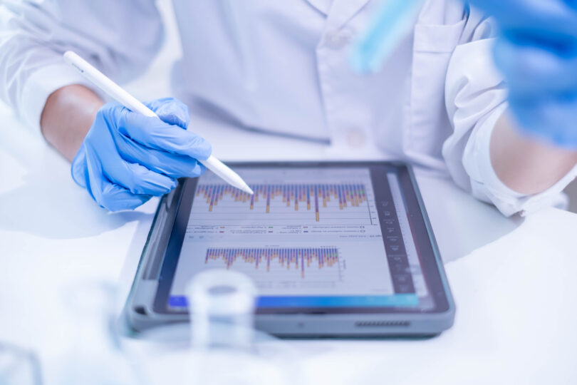 A woman in a laboratory setting writing notes on a document, appearing to be a scientist or doctor at work.
