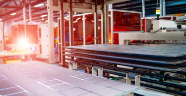 Workers assembling solar panels on a production line in a factory setting