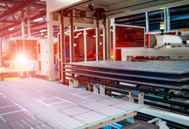 Workers assembling solar panels on a production line in a factory setting