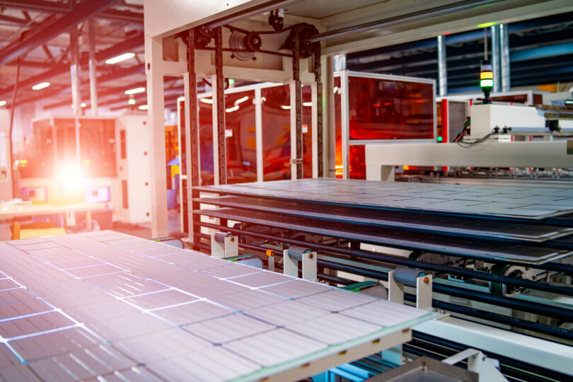 Workers assembling solar panels on a production line in a factory setting