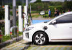 An electric vehicle plugged into a charging station in a parking lot.