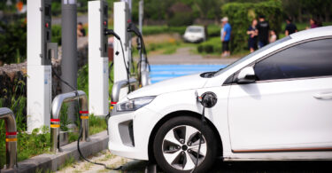 An electric vehicle plugged into a charging station in a parking lot.