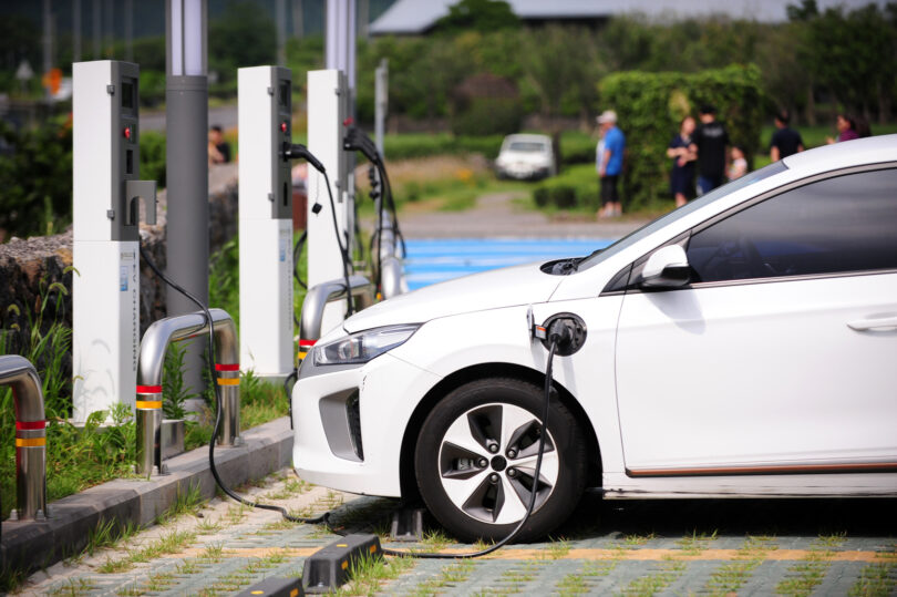 An electric vehicle plugged into a charging station in a parking lot.